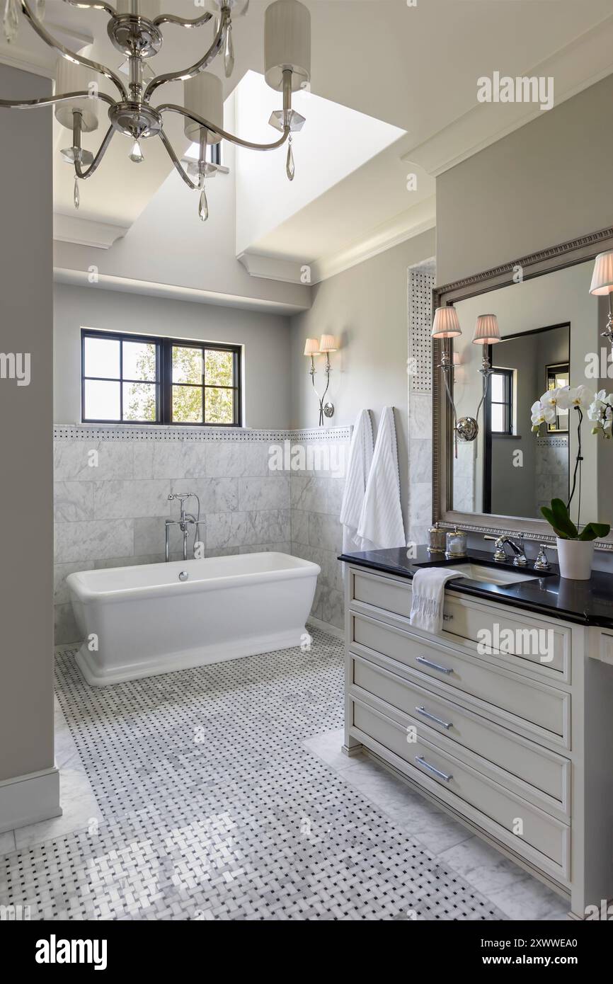 Bagno di alta qualità con vasca indipendente, piastrelle in marmo e finestra dormitorio Foto Stock