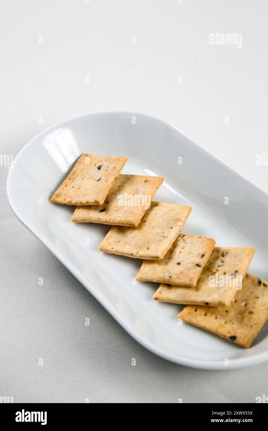 L'impasto madre scarta i cracker, i cracker Brown Rice Cracker, i cracker fatti in casa con i semi su una ciotola bianca da vicino. Foto Stock