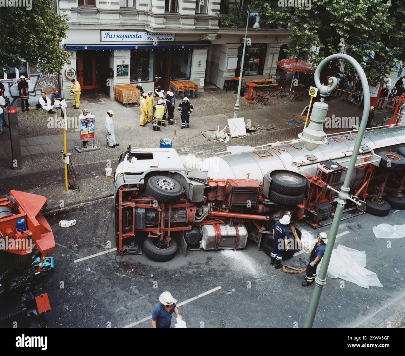 Una scena drammatica che mostra un incidente di camion rovesciato fuori da una trattoria a Berlino, 2005. Sono presenti soccorritori e osservatori di emergenza, catturando il caos e l'urgenza degli incidenti urbani. Foto Stock