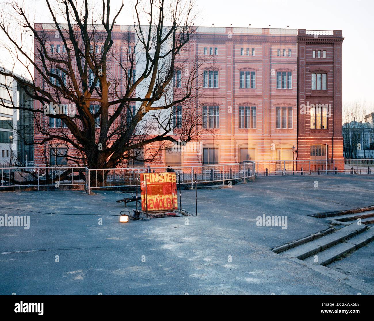 L'immagine raffigura la facciata della Bauakademie a Berlin-Mitte, coperta da uno schermo stampato attaccato a un'impalcatura. L'albero senza foglie di fronte e un cartello d'ingresso indicano una costruzione in corso, che simboleggia la ristrutturazione e la rinascita. Foto Stock
