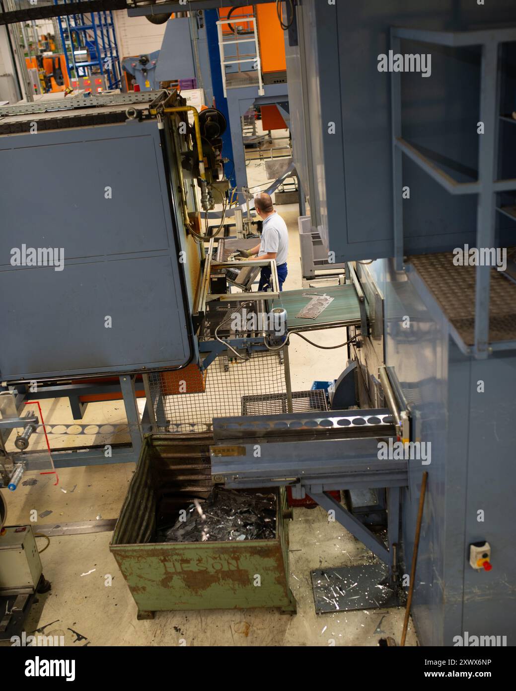 Un lavoratore gestisce macchinari avanzati in una fabbrica tedesca, mostrando i processi di produzione industriale. La scena mette in evidenza la complessità e l'efficienza delle moderne tecnologie di produzione in un ambiente professionale. Foto Stock