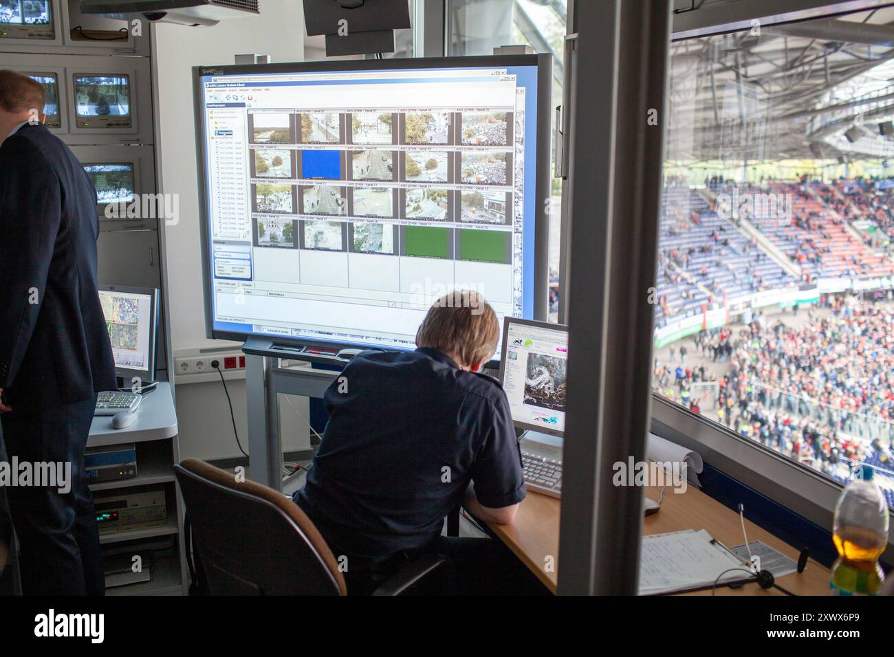 Il personale di sicurezza supervisiona la gestione della folla nella sala di controllo del Niedersachsenstadion di Hannover. La tecnologia di sorveglianza aiuta a monitorare i tifosi durante una partita del 2011, garantendo sicurezza e ordine. L'immagine cattura l'essenza di operazioni di sicurezza efficaci negli eventi sportivi. Foto Stock