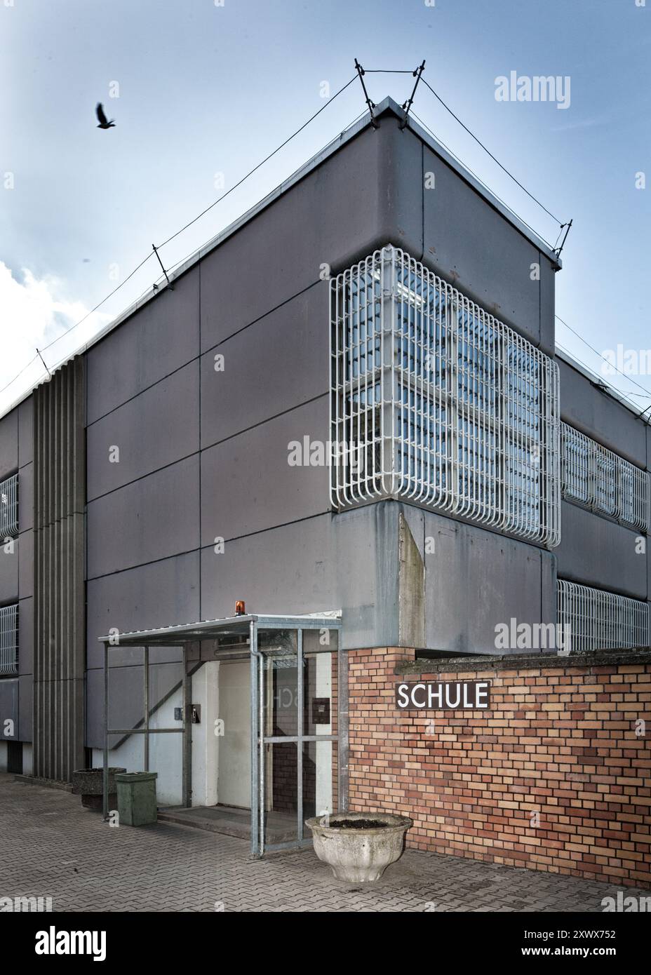 Un edificio scolastico all'interno del complesso carcerario di Tegel a Berlino, Germania, raffigurante la giustapposizione di istruzione e incarcerazione. La struttura, con il suo design austero, funge da metafora per la libertà di conoscenza all'interno del confinamento. Foto Stock