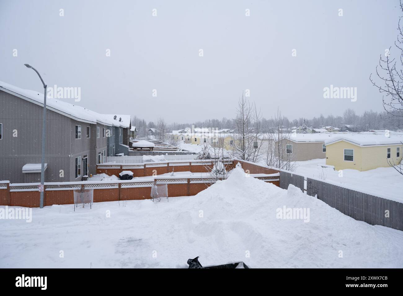 Paesaggio innevato con case mobili in un parcheggio per roulotte, Anchorage, Alaska. La scena serena può simboleggiare metaforicamente la resilienza e la tranquilla bellezza dell'inverno. Foto Stock