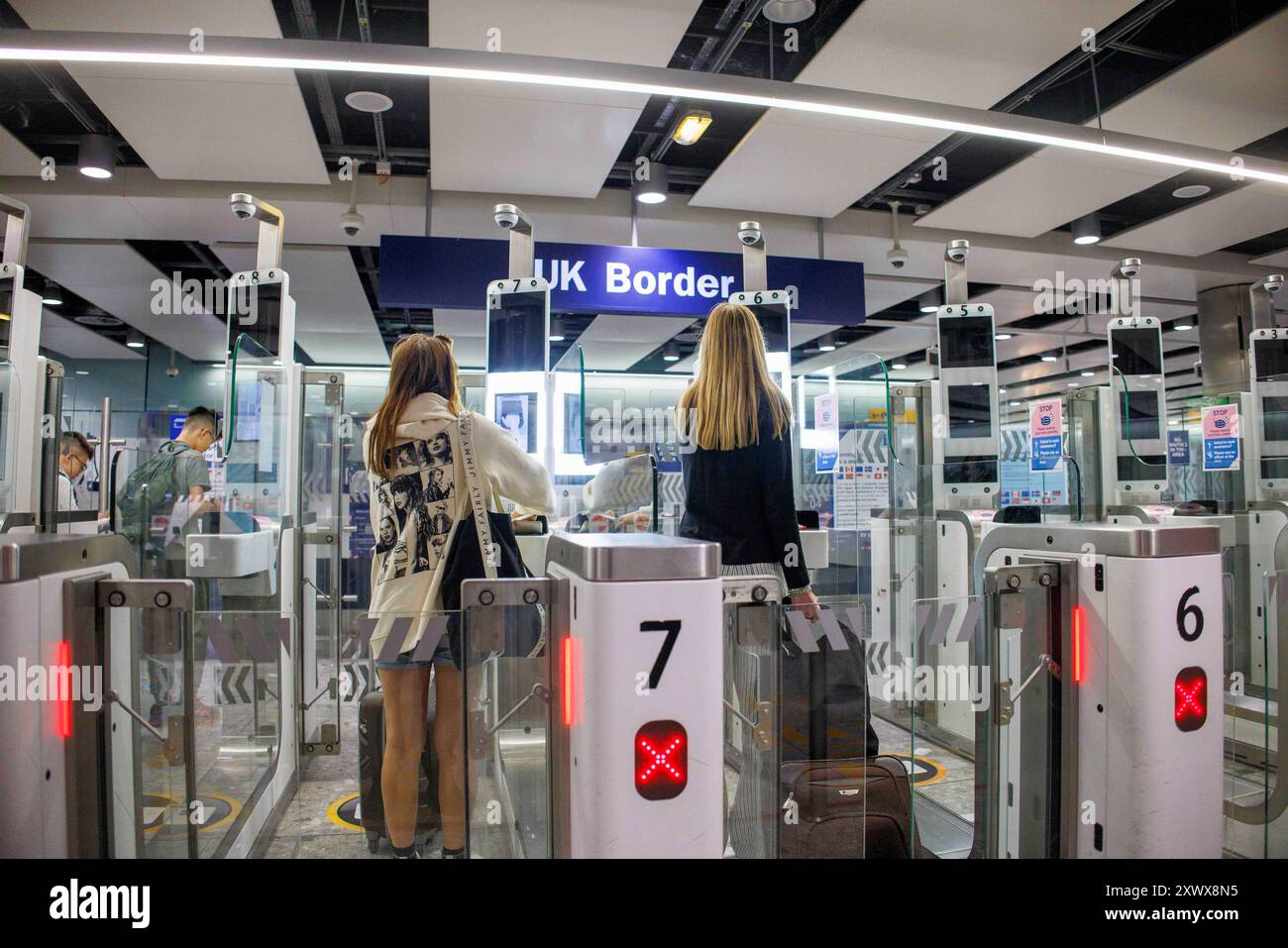 Passeggeri aerei in arrivo al gate del check-in al confine con il Regno Unito al Terminal 3 di Heathrow. Usano il riconoscimento facciale al cancello del check-in automatico. Foto Stock