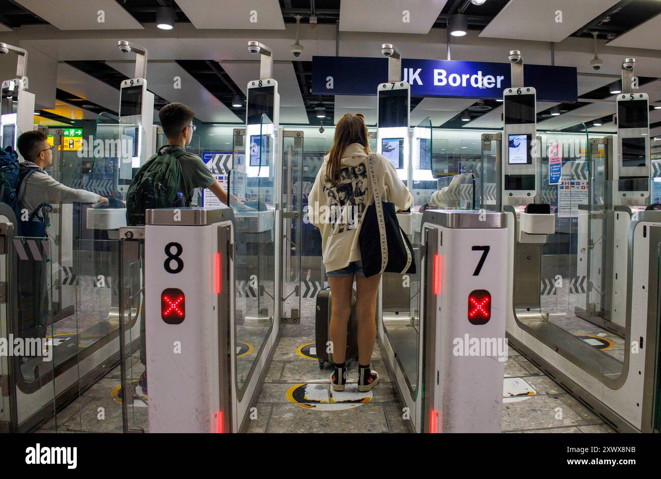 Passeggeri aerei in arrivo al gate del check-in al confine con il Regno Unito al Terminal 3 di Heathrow. Usano il riconoscimento facciale al cancello del check-in automatico. Foto Stock