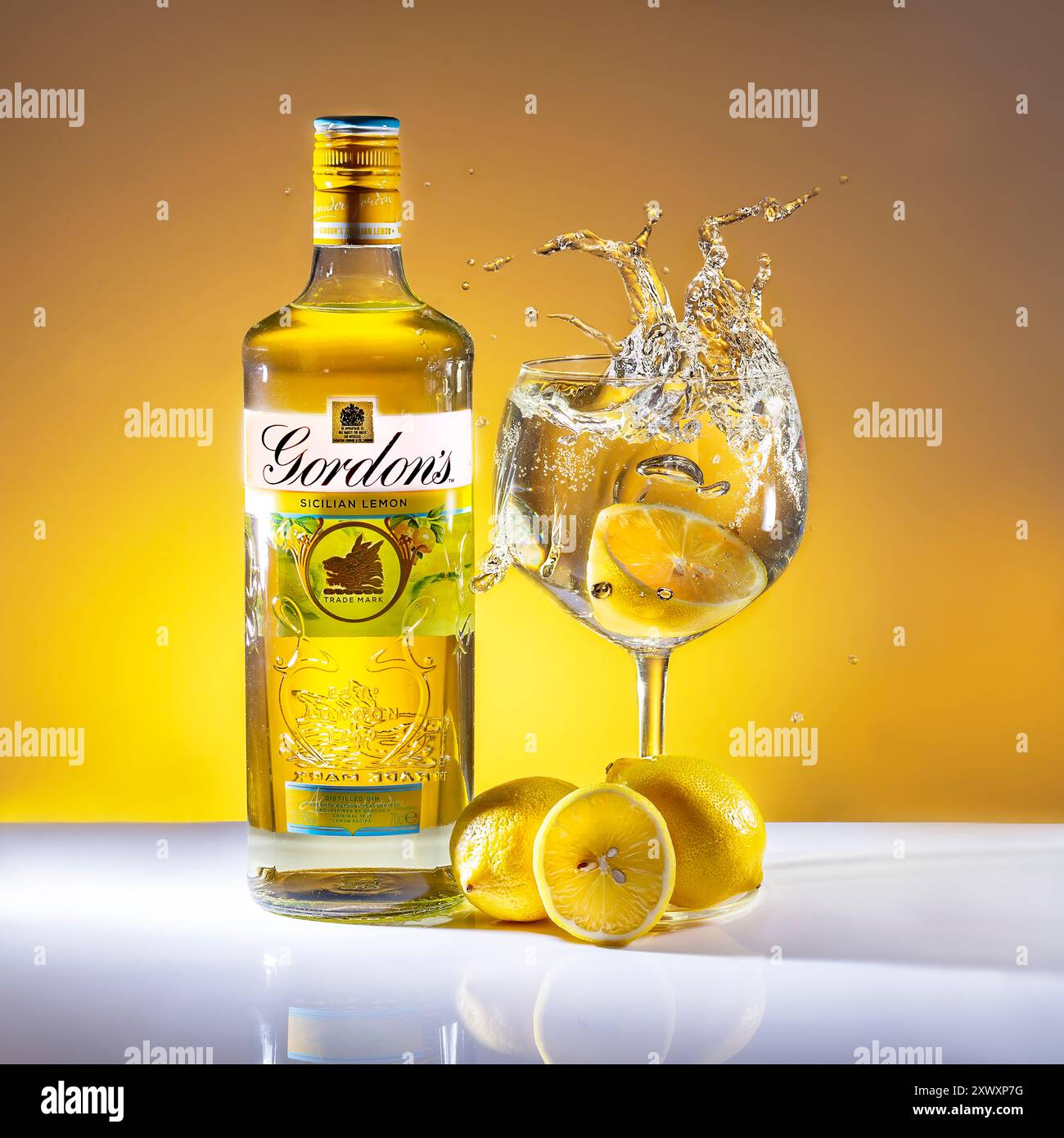 Bottiglia di Gin di limone siciliano Gordons, limoni e gin in vetro con spruzzi Foto Stock