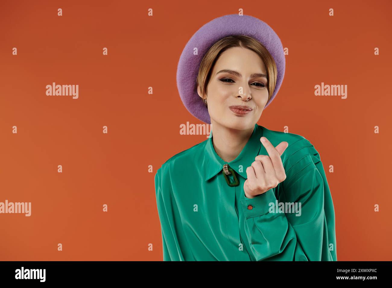 Una donna dal look grunge elegante crea un segno di cuore con la mano. Foto Stock