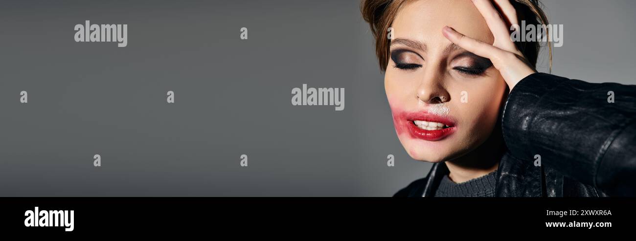 Una donna con rossetto macchiato si posa su uno sfondo grigio. Foto Stock