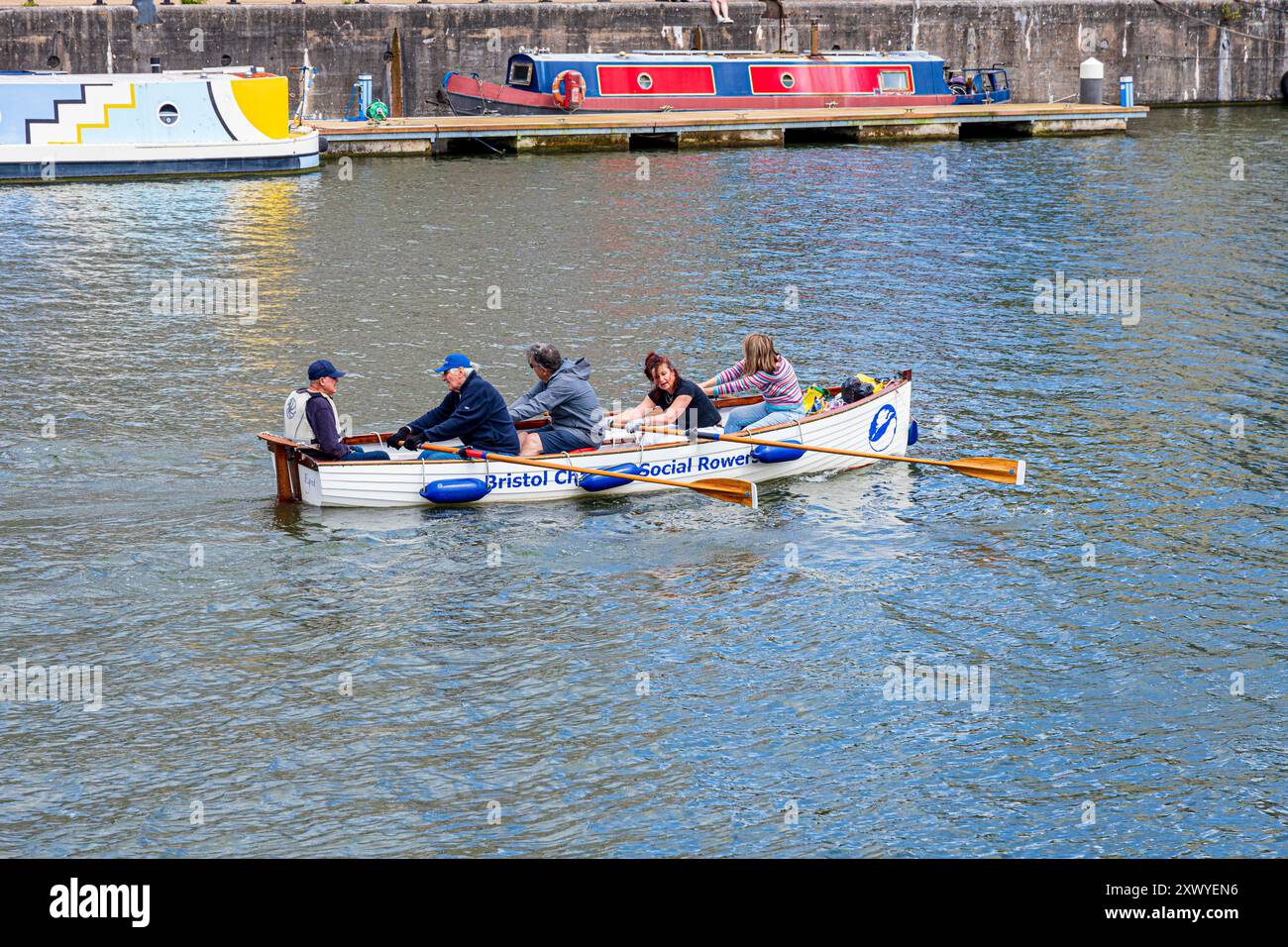 La barca a remi in stile Senna "Egret" con membri dei Bristol Channel Social Rowers nel porto galleggiante, Bristol Docks, Bristol City, Inghilterra Regno Unito Foto Stock
