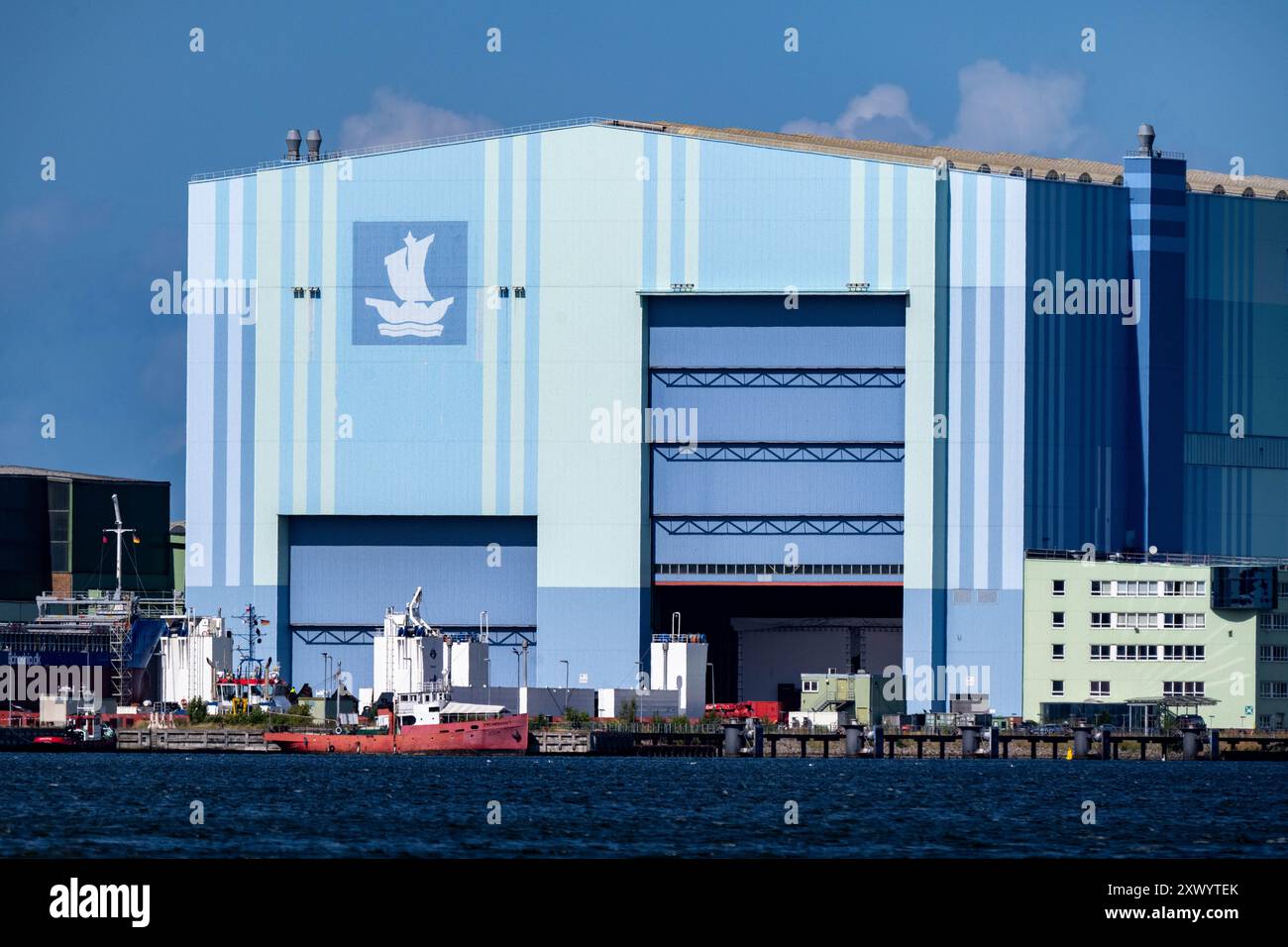 Stralsund, Germania. 21 agosto 2024. Vista del parco industriale marittimo di Volkswerft con la sala della costruzione navale. La città di Stralsund ha acquistato il cantiere navale in seguito all’insolvenza del gruppo MV-Werften e ha sviluppato un parco commerciale marittimo, che ora ospita diverse società. La città anseatica di Stralsund ha risolto il contratto di locazione con Fosen Werft GmbH per la grande sala di costruzione navale dell'ex cantiere navale Volkswerft Stralsund prima del previsto.(a dpa: "Stralsund separa da Fosen sul sito Volkswerft") credito: Stefan Sauer/dpa/Alamy Live News Foto Stock