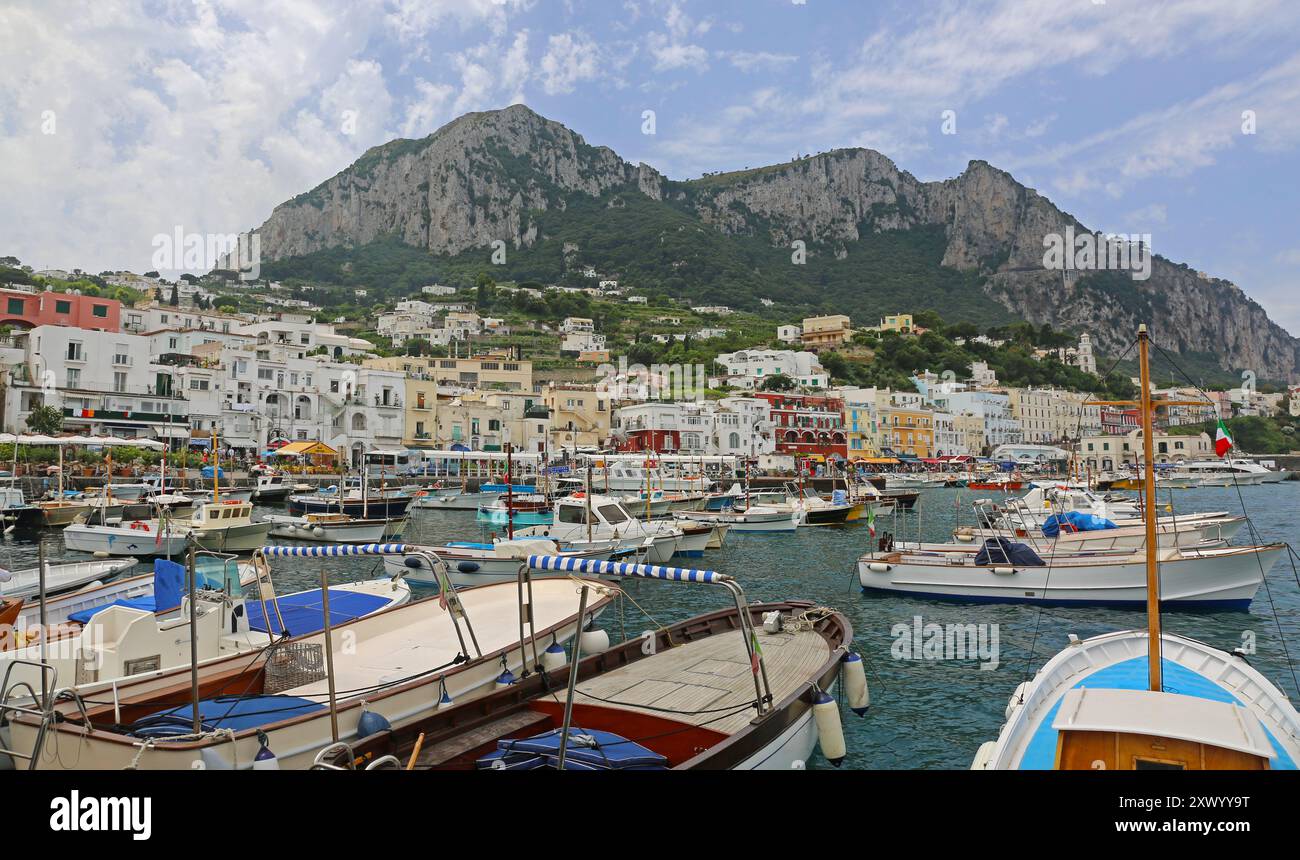 Capri, Italia - 26 giugno 2014: Pescherecci ormeggiati e piccole imbarcazioni nel porto di Marina grande all'Isola con montagna in background, viaggi estivi. Foto Stock