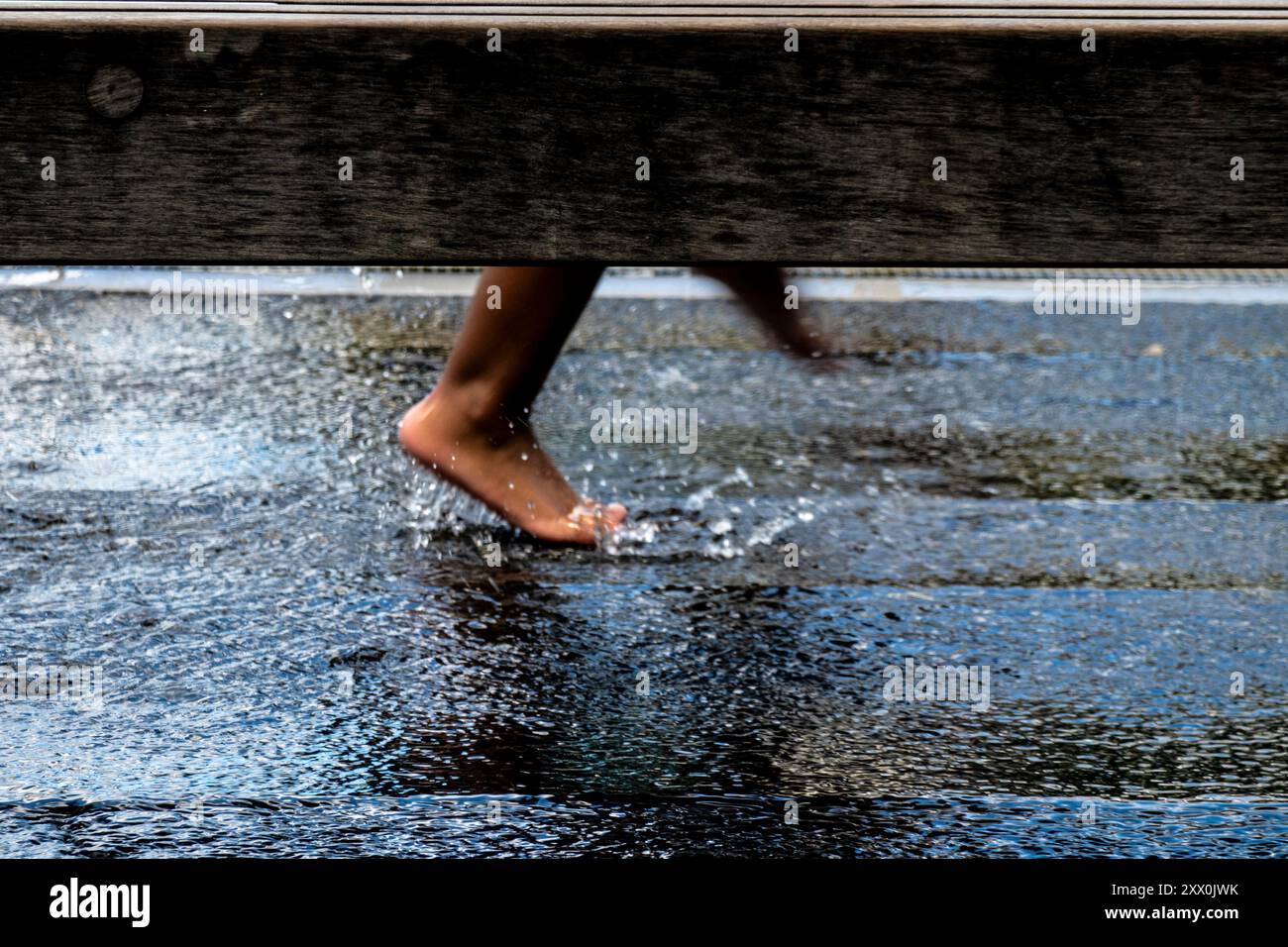I piedi dei bambini Brown che scorrono attraverso l'acqua nell'High Line Park, New York, New York, Stati Uniti Foto Stock