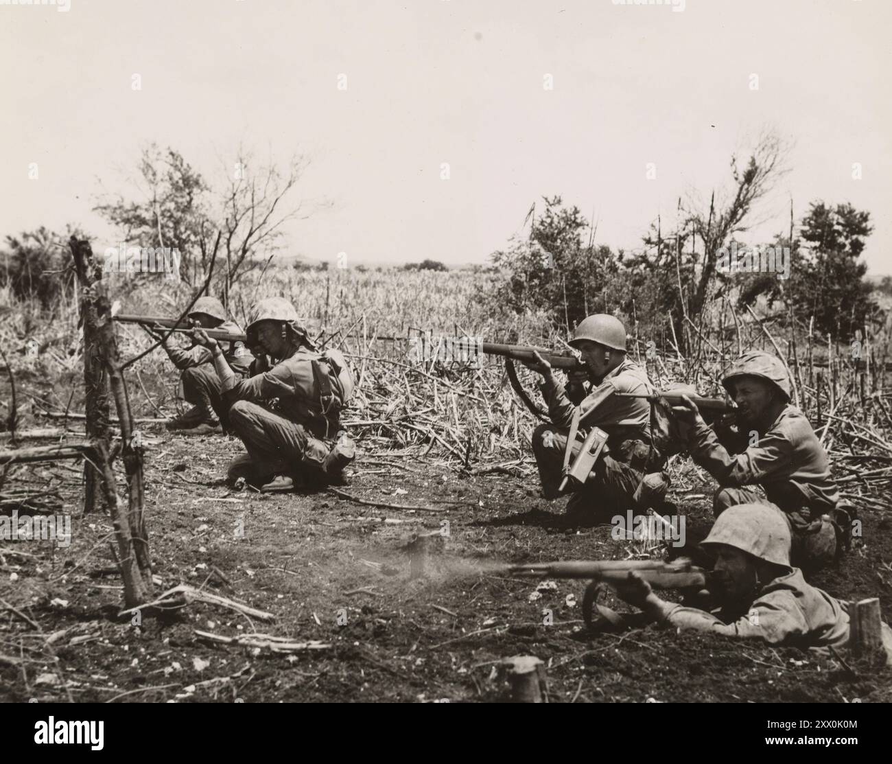 Seconda guerra mondiale, Battaglia di Tinian. Parte della campagna del Pacifico. Dal 24 luglio al 1° agosto 1944 i marines che salpano sull'isola di Tinian cadono in posizione di fuoco quando il nemico viene avvistato. Il Leatherneck in primo piano, che ha approfittato di un cratere a guscio, ha appena sparato il suo fucile. Gli altri, utilizzando una posizione di inginocchiamento, sono pronti a premere il grilletto. Foto Stock
