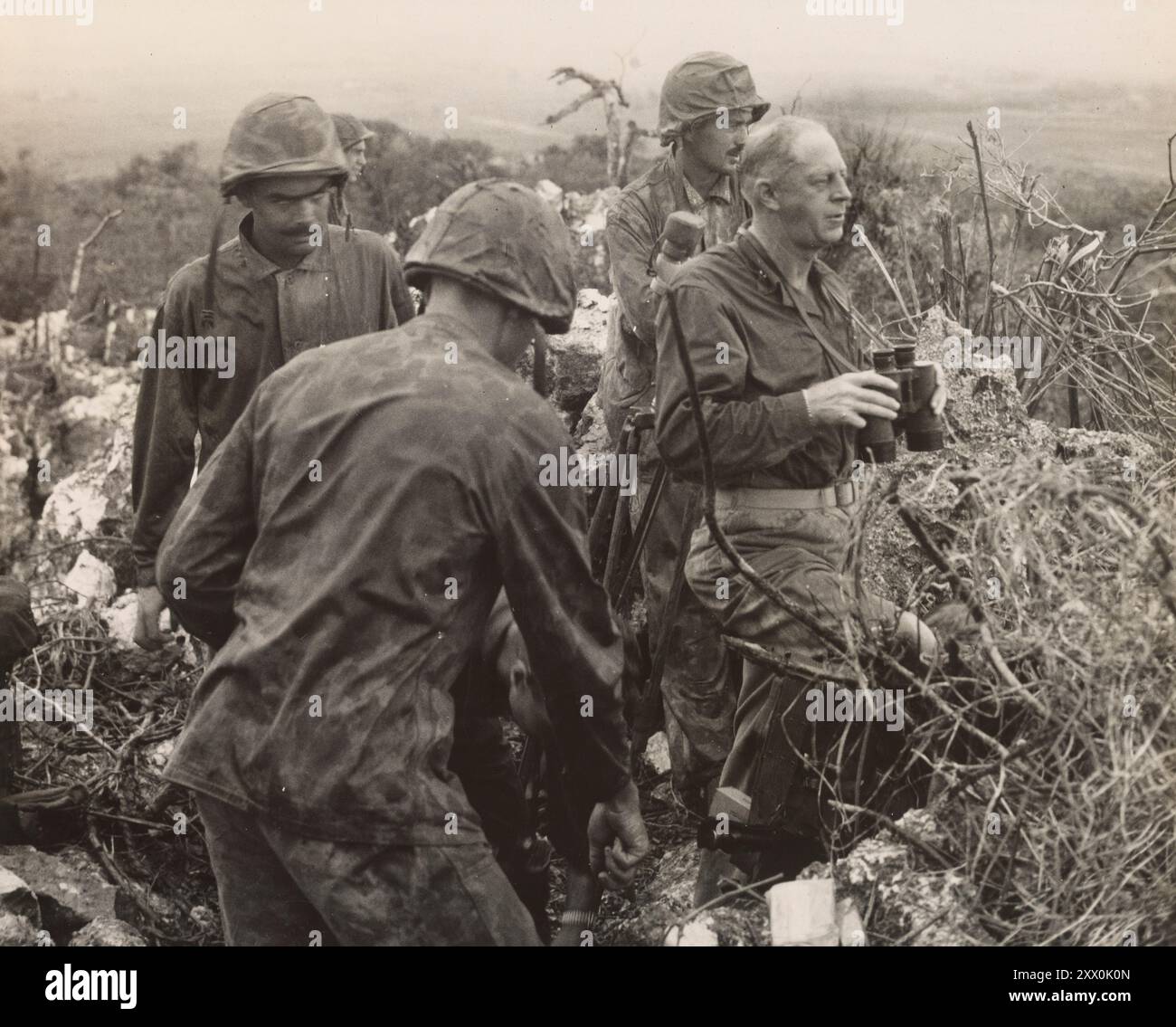 Seconda guerra mondiale, Battaglia di Tinian. Parte della campagna delle Isole Marianne e Palau del Pacific Theater. 24 luglio – 1 agosto 1944 osservatore in prima linea. Da un posto di osservazione in cima al Monte lasso, il generale di brigata della Marina Merritt A. Edson, (a testa nuda), Guadalcanal e Tarawa veterano, tiene d'occhio le sue truppe mentre assaltano le posizioni giapponesi su Tinian, l'ultimo del gruppo Mariana che sarà conquistato dai Leathernechs. Foto Stock