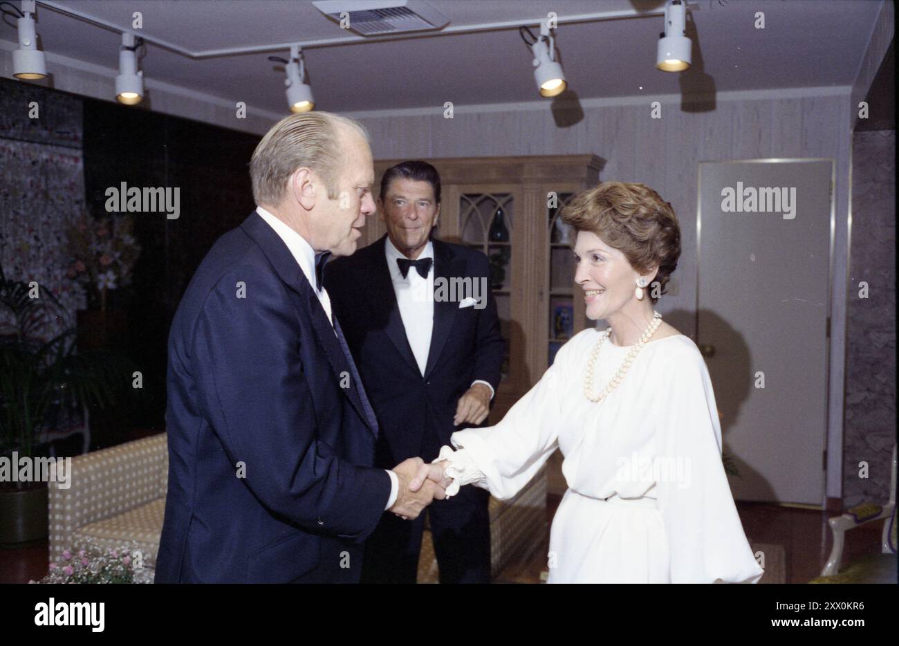 Gerald R. Ford, Nancy Reagan, Ronald Reagan – Gerald Ford e Nancy Reagan stringono la mano; Ronal Reagan in background; abbigliamento formale – viaggio in campagna in California; prima di salute alla cena presidenziale - Beverly Hills, California. 1976, 19 agosto Foto Stock