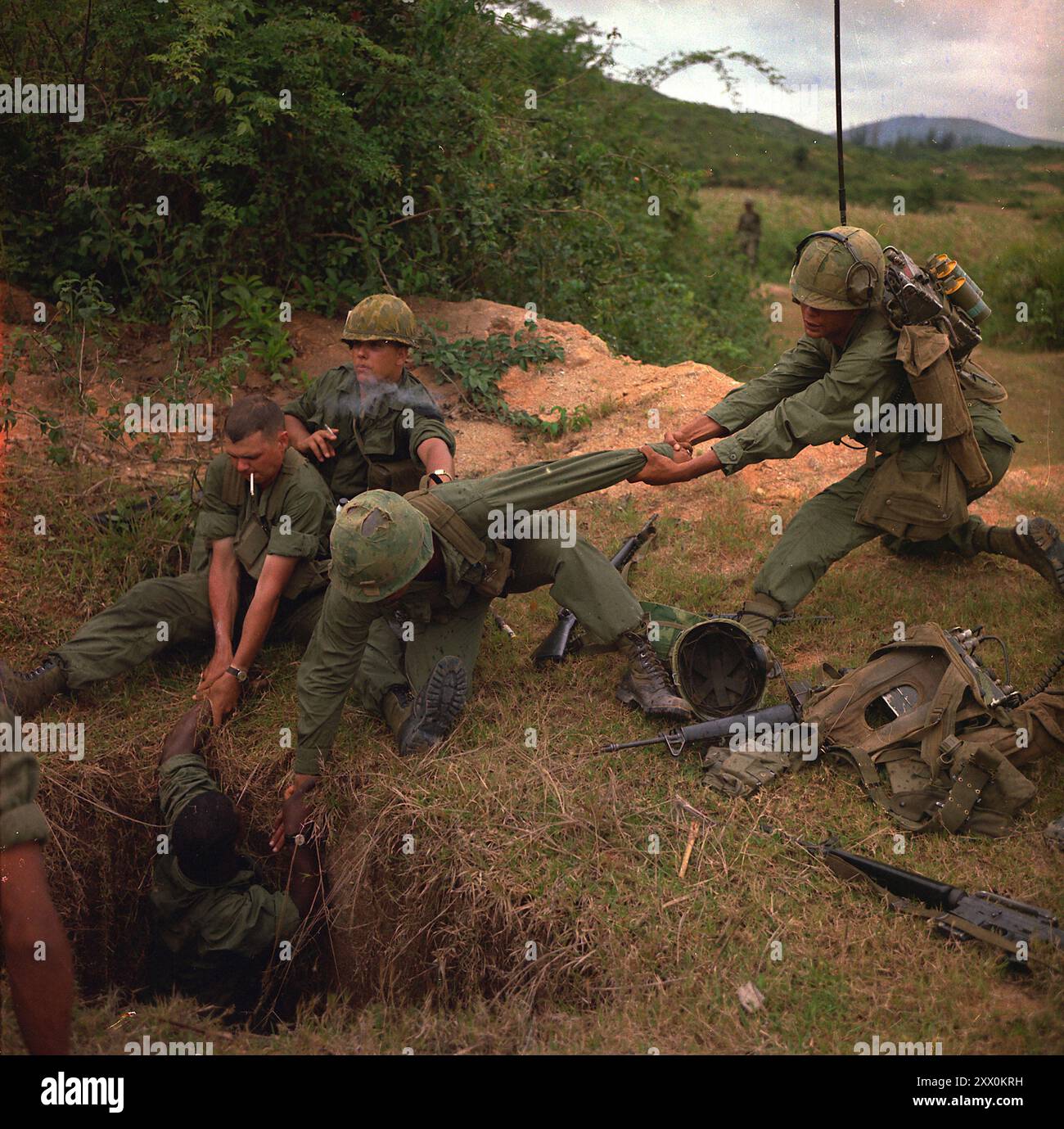 Guerra del Vietnam. Operazione 'Oregon', una missione di ricerca e distruzione condotta da un plotone di fanteria della Troop B, 1st Reconnaissance Squadron, 9th Cavalry, 1st Cavalry Division (Airmobile), tre chilometri ad ovest di Duc Pho, provincia di Quang Ngai. Un fanteria viene abbassato in un tunnel dai membri del plotone di ricognizione. 24 aprile 1967. Foto Stock