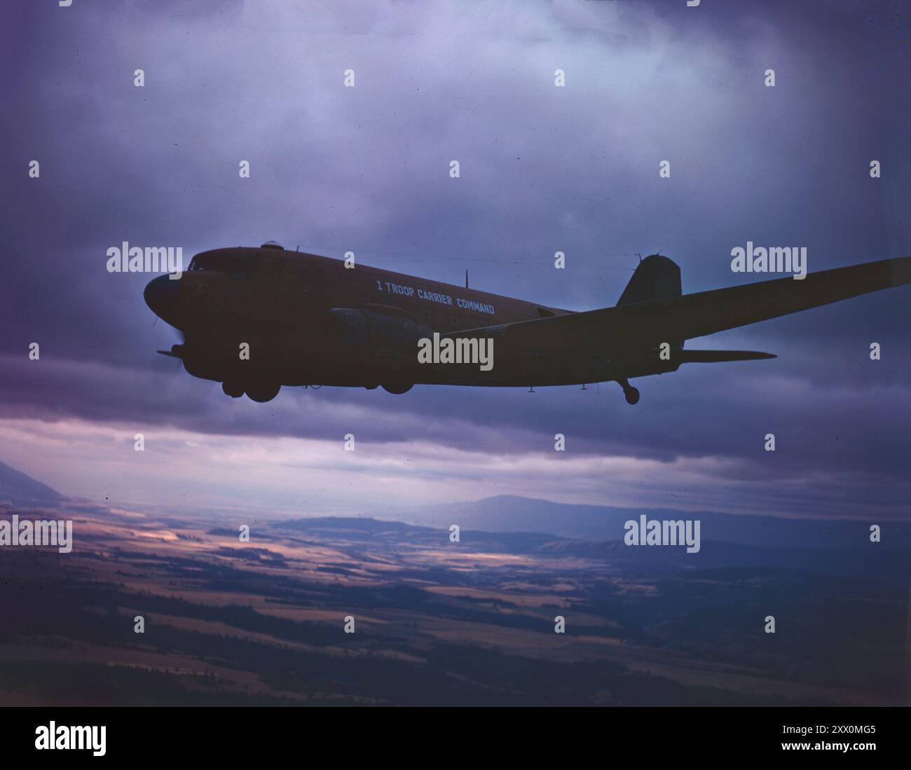 Seconda guerra mondiale operazione Fire Fly. Un C-47 del First Troop Carrier Command vola sopra la campagna dell'Oregon. CA. 1945 nell'aprile 1945 il 555th è stato assegnato come 300 componente di un gruppo di sforzo militare più grande di 2.700 persone assegnato all'operazione Fire Fly nelle regioni del servizio forestale degli Stati Uniti 1,4,5, e 6. Fire Fly è stato organizzato come un massiccio sforzo civile/militare per combattere la prevista minaccia di fuoco nelle terre selvagge da parte delle bombe in mongolfiera giapponesi, che erano arrivate in numero crescente lungo la costa occidentale (e fino al Michigan) dall'agosto 1944. Anche se non era un kno pubblico Foto Stock