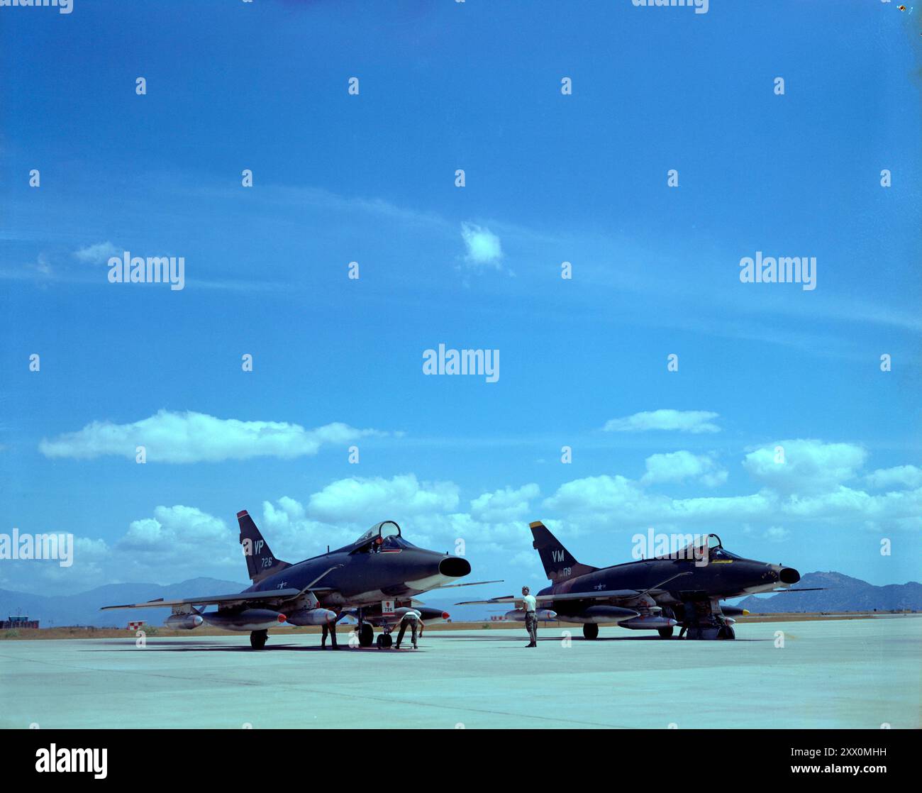 Guerra del Vietnam. Phan Rang AB, Vietnam del Sud… Vista frontale di un aereo F-100 della U.S. Air Force armato dal personale di manutenzione della 435th Munitions. Accanto c'è un altro F-100, soprannominato "No Smut". Febbraio 1970 Foto Stock