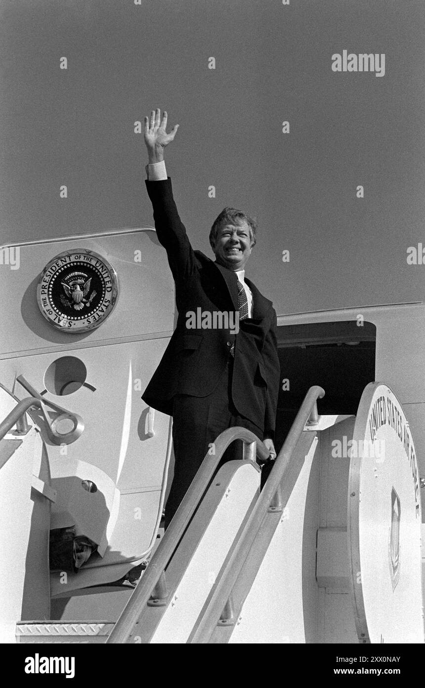 Il presidente Jimmy Carter si agita alla folla che e' a disposizione per salutarlo mentre esce dall'Air Force I.. Foto Stock