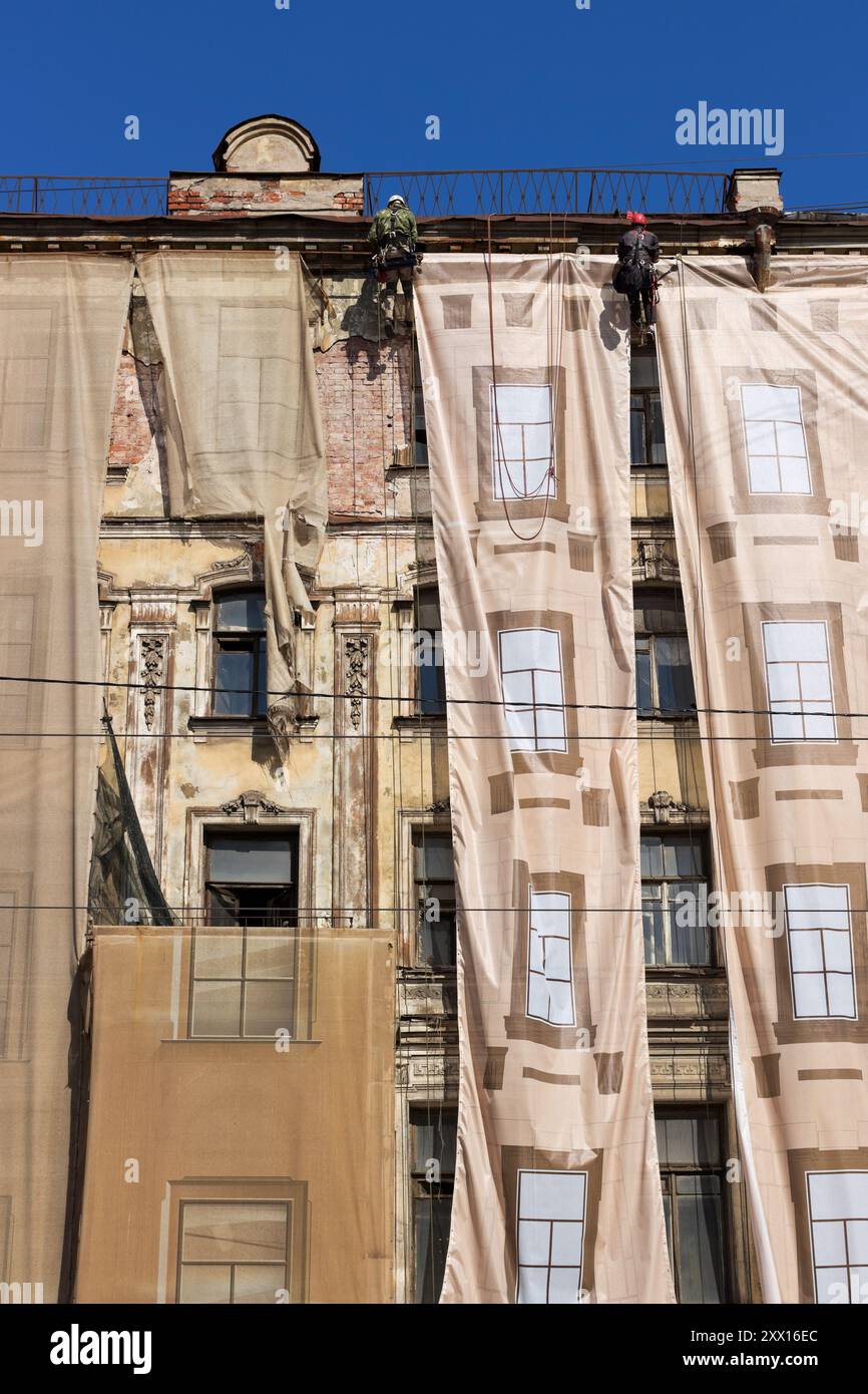 Lavori di riparazione-costruzione della facciata di un vecchio edificio ad un'altitudine vicino al tetto Foto Stock