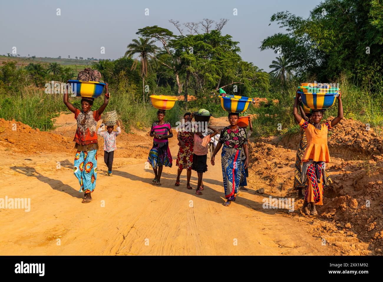 Donne che trasportano merci e acqua in testa sulla pessima strada tra Tshikapa e Kananga, Kasai, Repubblica Democratica del Congo, Africa Foto Stock