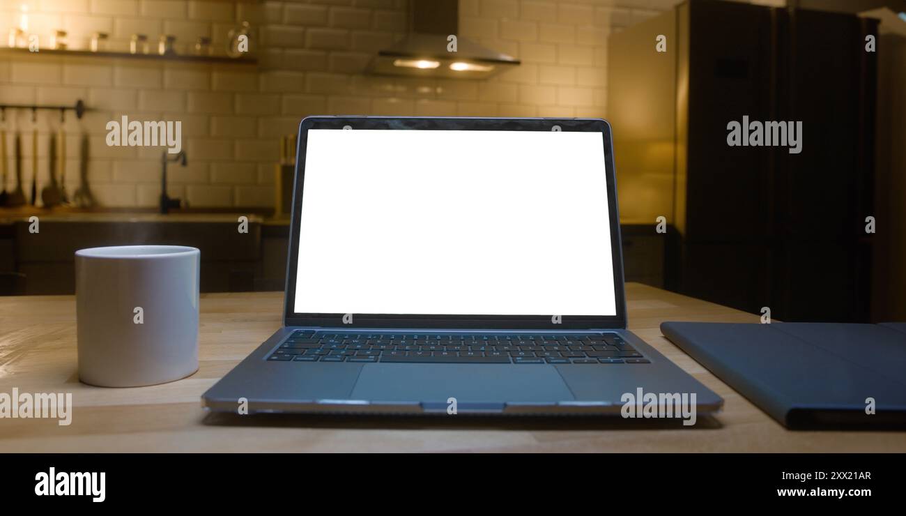 Un notebook con uno schermo bianco con un tablet, una tazza di caffè e documenti su un tavolo di legno, sottolineando la produttività e l'organizzazione. Foto Stock