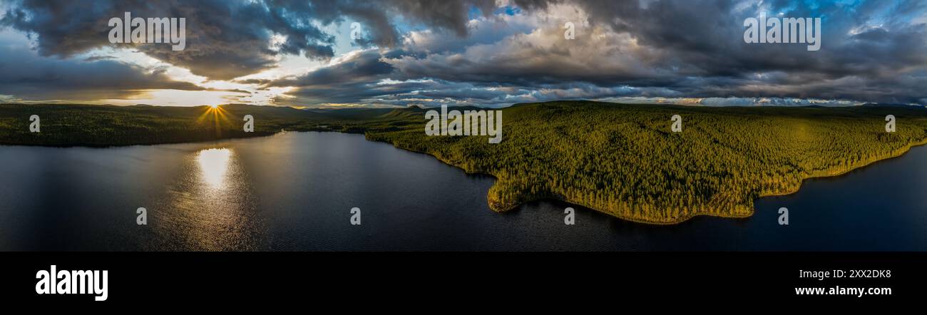 Vista aerea panoramica del tramonto sul lago Hällsjön, con riflessi dorati sull'acqua, mentre le fitte foreste incorniciano il paesaggio svedese Foto Stock