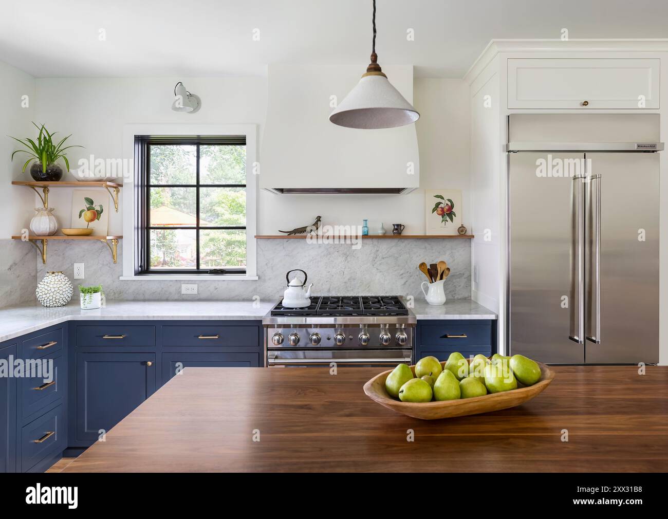 Cucina con armadi blu, ripiani in marmo bianco e ripiani in noce Foto Stock