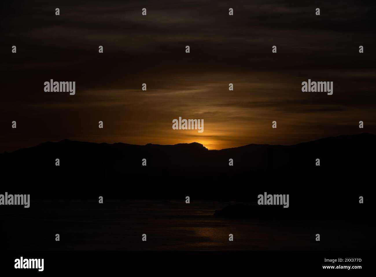 Foto del sole che tramonta sull'oceano e sulla città di Benidorm in Spagna Foto Stock