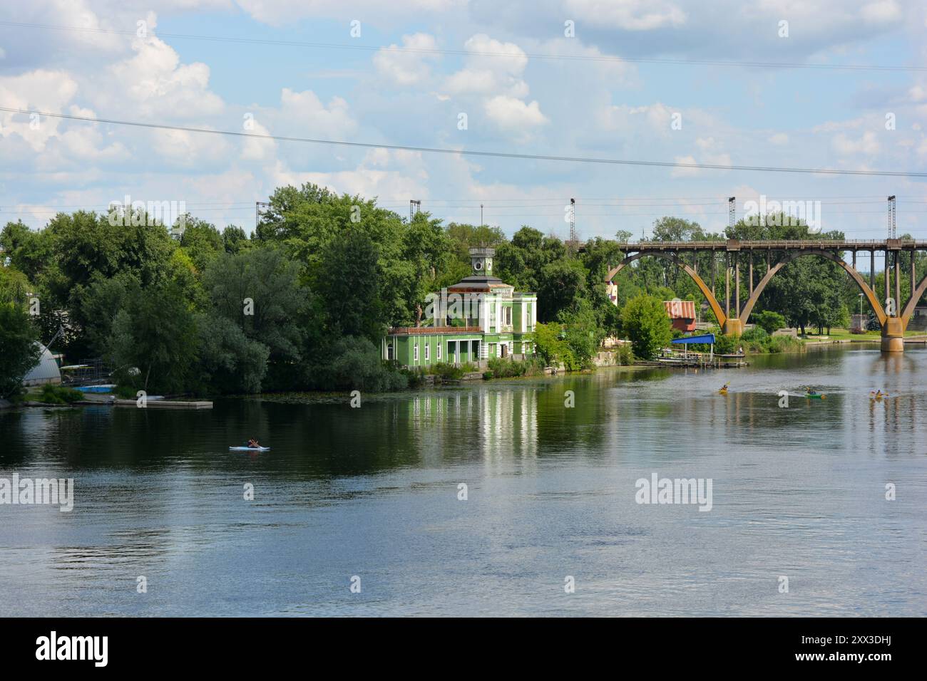 Splendida vista sull'ampio e lungo fiume Dnipro blu. Paesaggi, argini in mattoni grigi con alberi verdi, nuovi cantieri e ponti nella città di Dnipro. Foto Stock