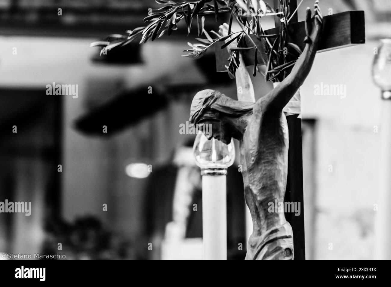 Particolare di un antico crocifisso ligneo sul quale è stato posto un ramoscello d'ulivo come segno di pace Foto Stock