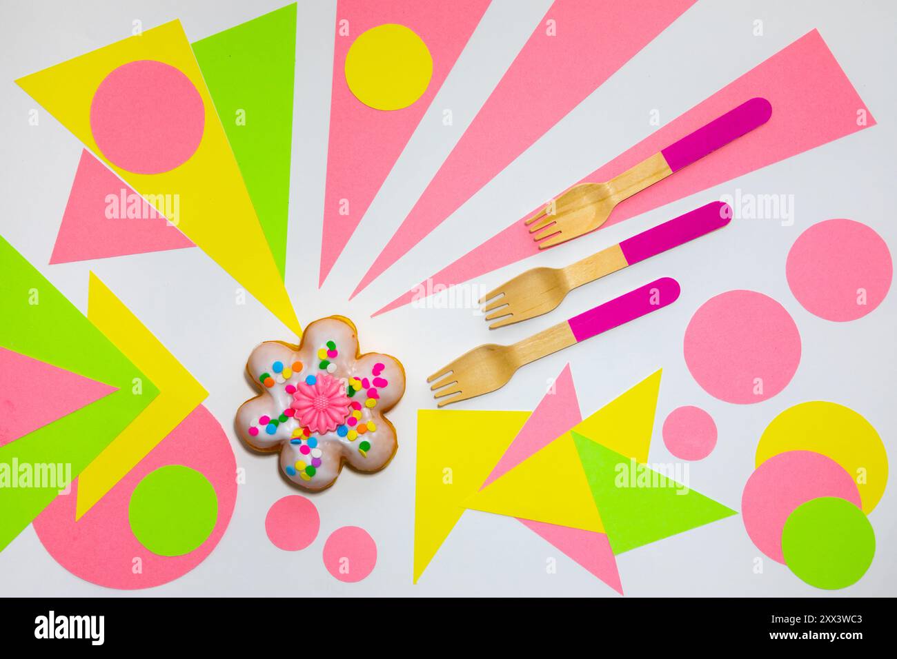 Ciambella a forma di fiore con cucchiai di legno su sfondo multicolore Foto Stock