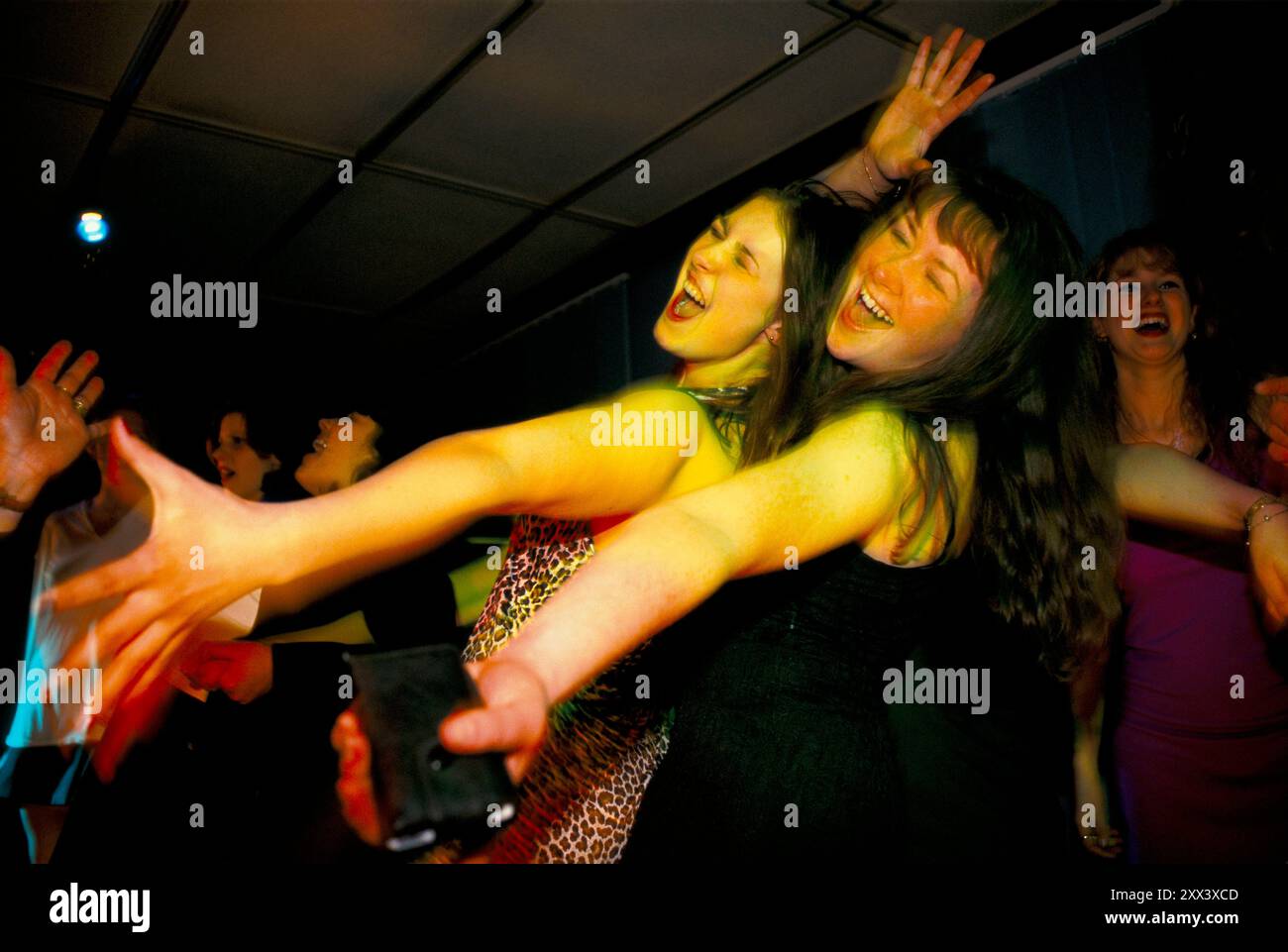 Giovani donne che ballano insieme le braccia allungate mentre cantano lungo la band sul palco. Pista da ballo affollata in occasione di un evento per sole ragazze, un nightclub. Worcestershire Inghilterra anni '1998 1980 UK HOMER SYKES Foto Stock