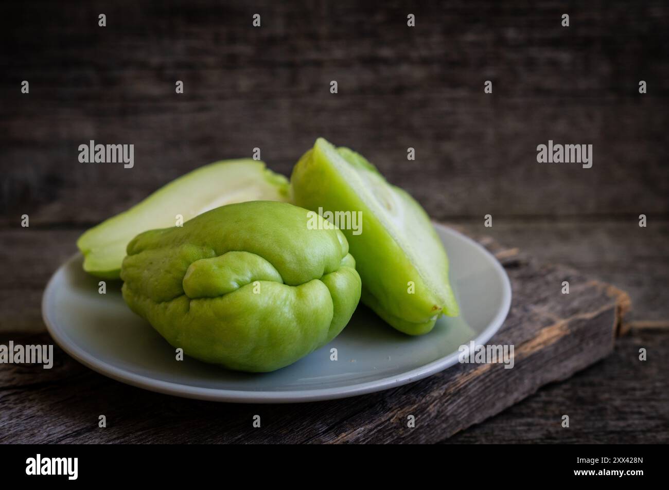 Zucca d'India verde fresca, cayote su fondo di legno, (Sechium edulis) Foto Stock