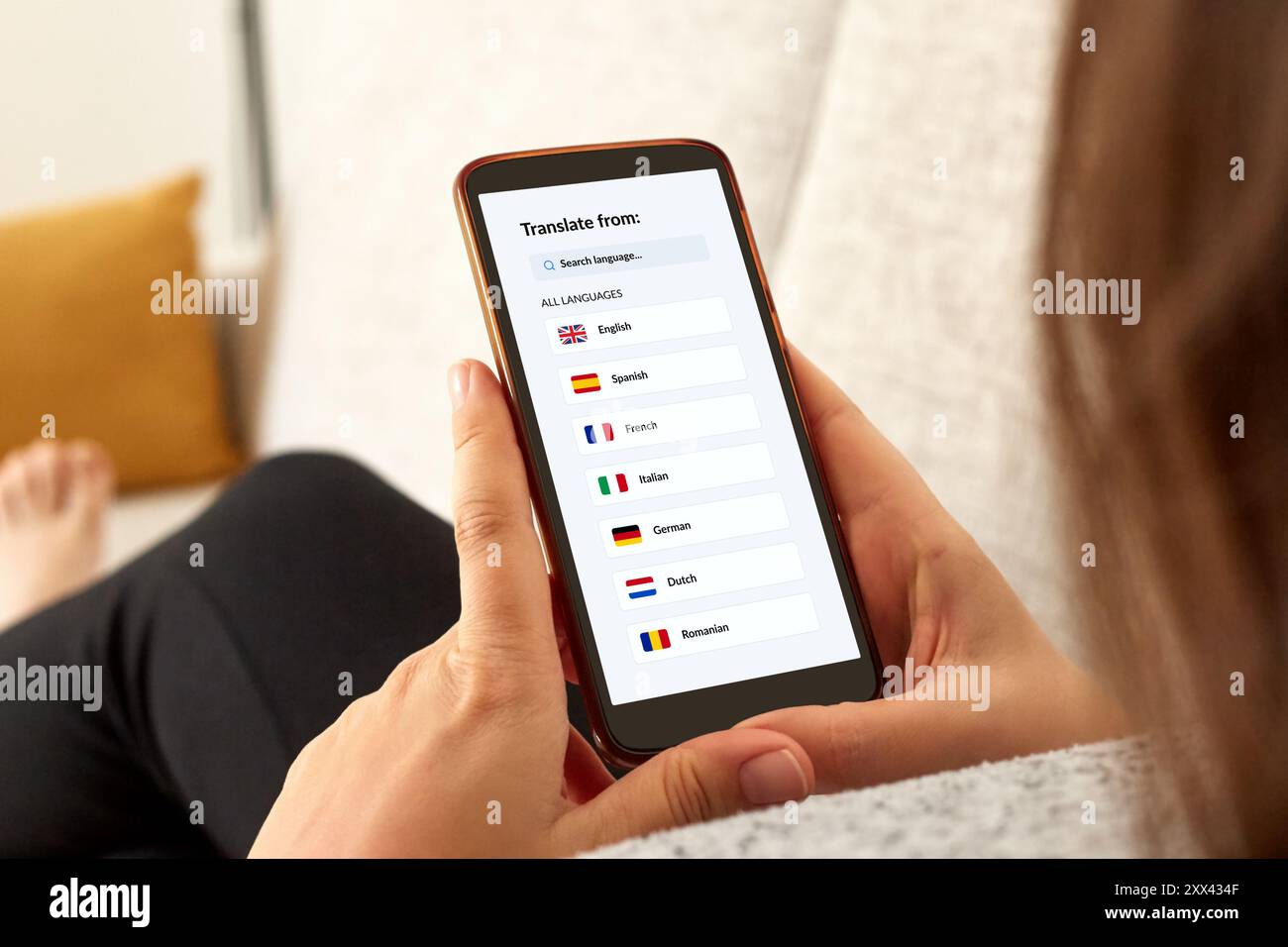 Foto ravvicinata di una ragazza su un divano utilizzando l'app per traduttori linguistici con smartphone mobile. Foto Stock