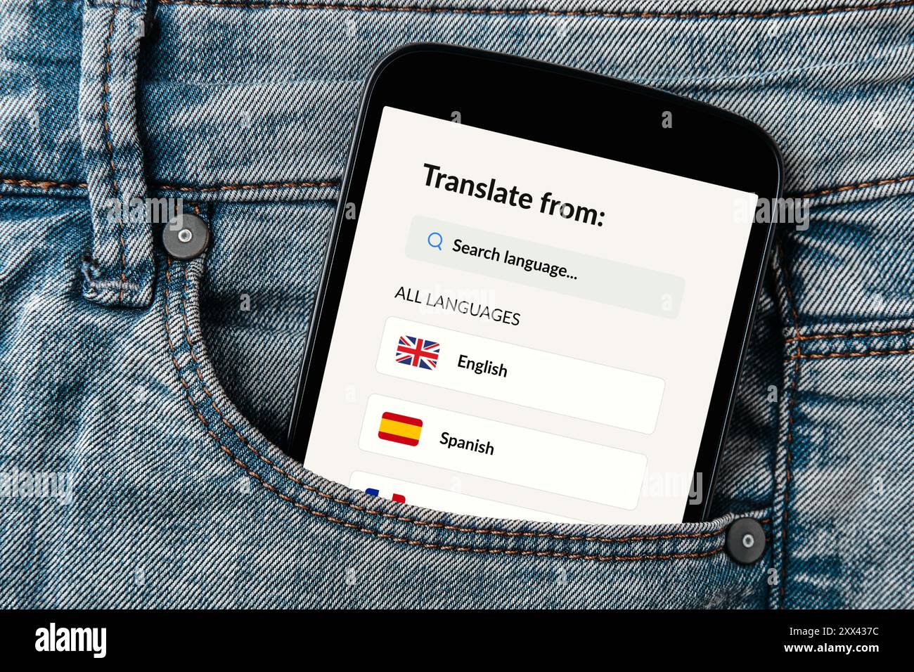 Applicazione traduttrice visualizzata sullo schermo di uno smartphone che esce dalla tasca di un jeans. Foto Stock