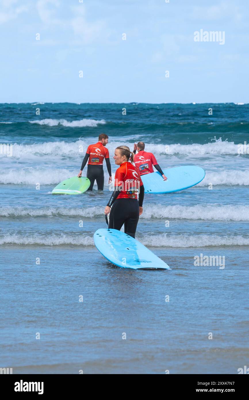 Principianti di surf che tengono una lezione di surf in mare a Towan Beach a Newquay in Cornovaglia nel Regno Unito. Foto Stock