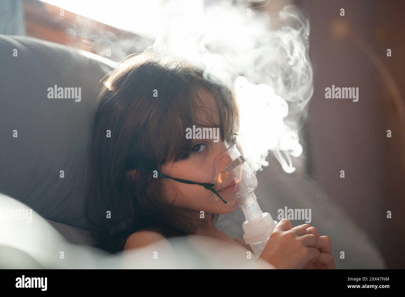 Ragazza malata con maschera inalatoria e vapore escono Foto Stock