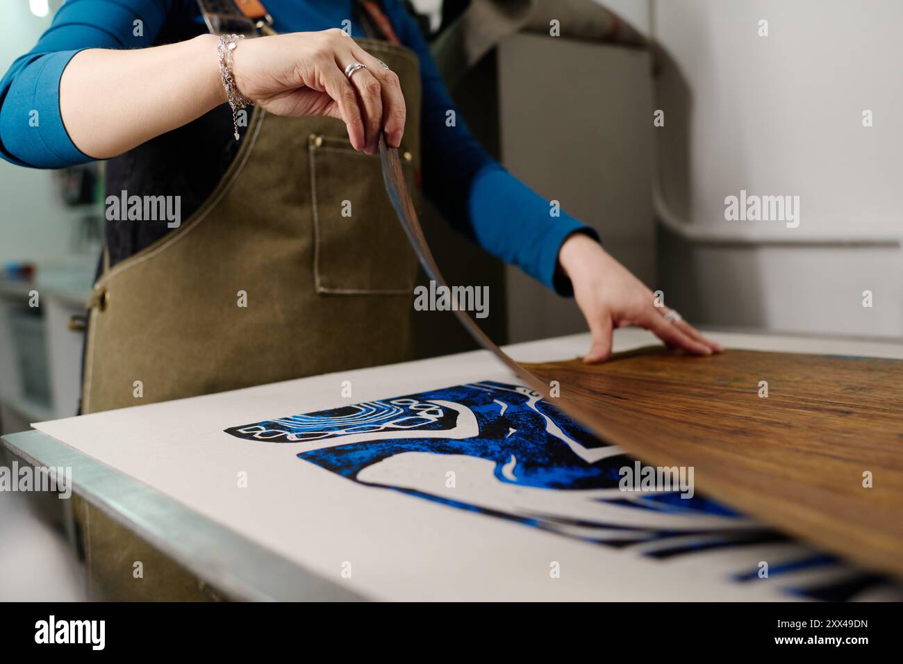 Mano di una giovane lavoratrice del moderno centro tipografico che crea nuove opere d'arte mentre si trova accanto alla macchina da stampa in officina Foto Stock