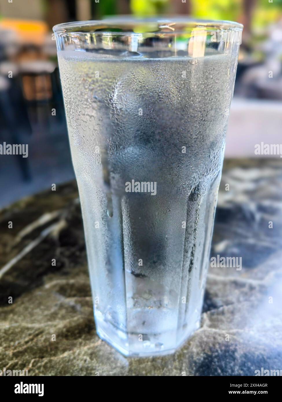 Dissetati: Un bicchiere di acqua ghiacciata servito al bar, concetto congelato con effetto bokeh Foto Stock