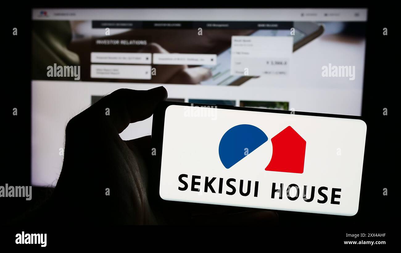 Persona che possiede uno smartphone con il logo dell'azienda giapponese Sekisui House Ltd. Di fronte al sito Web. Mettere a fuoco il display del telefono. Foto Stock