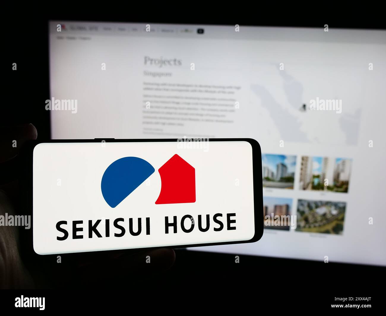 Persona che possiede un telefono cellulare con il logo della società giapponese Sekisui House Ltd. Di fronte alla pagina Web aziendale. Mettere a fuoco il display del telefono. Foto Stock