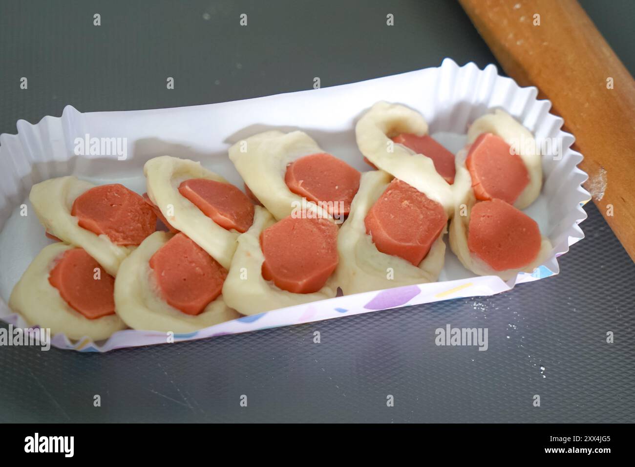 Panino con salsicce inserito in una lunga tazza di carta da forno. Foto Stock