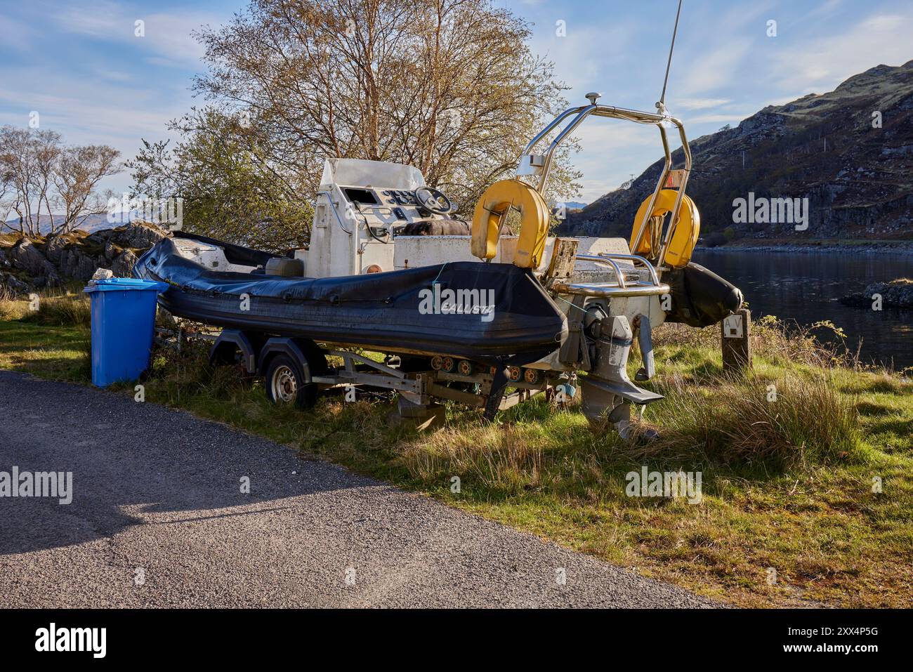 Sulla riva di Glenuig Bay, un motore in gomma abbandonato e un motore su un rimorchio arrugginito. Glenuig, Scozia Foto Stock