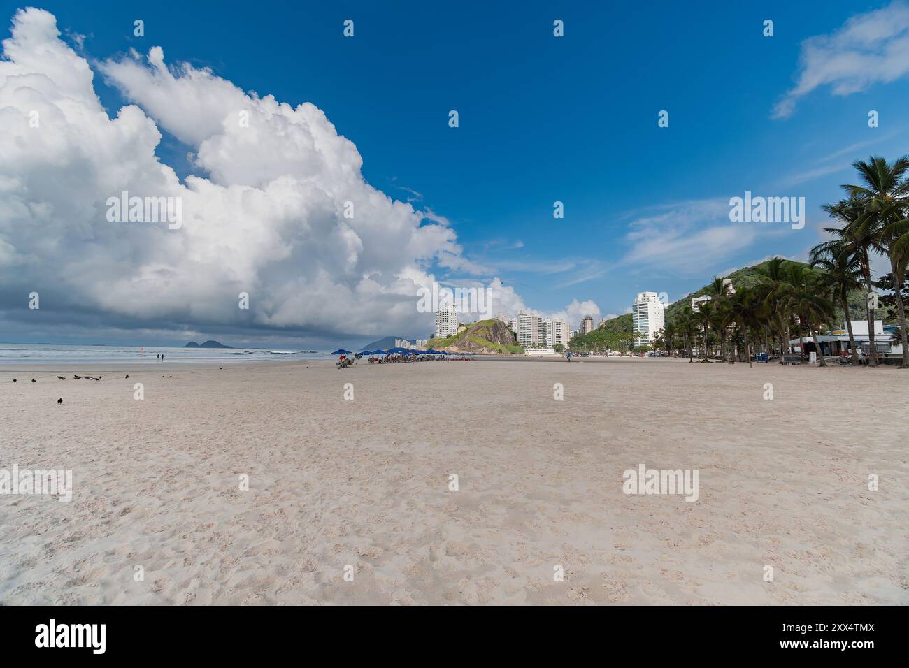 Mattinata a Enseada Beach in una splendida giornata con alcune nuvole, un'ampia vista della spiaggia, del mare e delle colline sullo sfondo. Guaruja - SP, Foto Stock