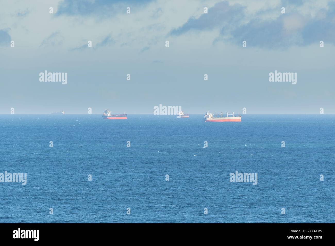 Navi da carico viste lontano dalla costa in mezzo al mare. Foto Stock