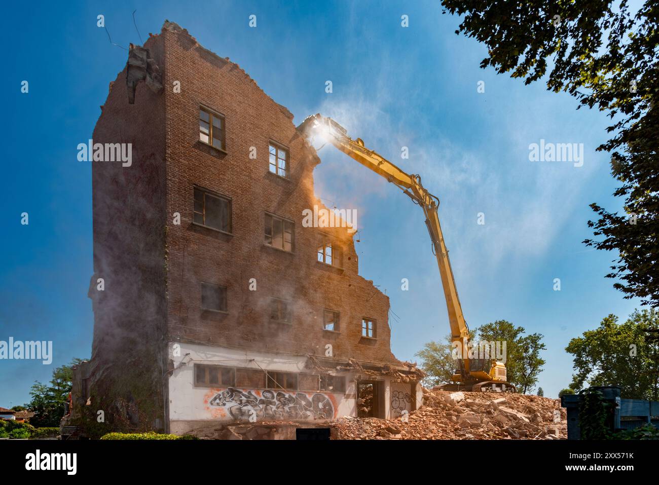 Demolizione di vecchia struttura industriale in mattoni con escavatore con pinze frantumatrici idrauliche per calcestruzzo, demolizione di ex mulino in corso Savona, Asti, IT Foto Stock
