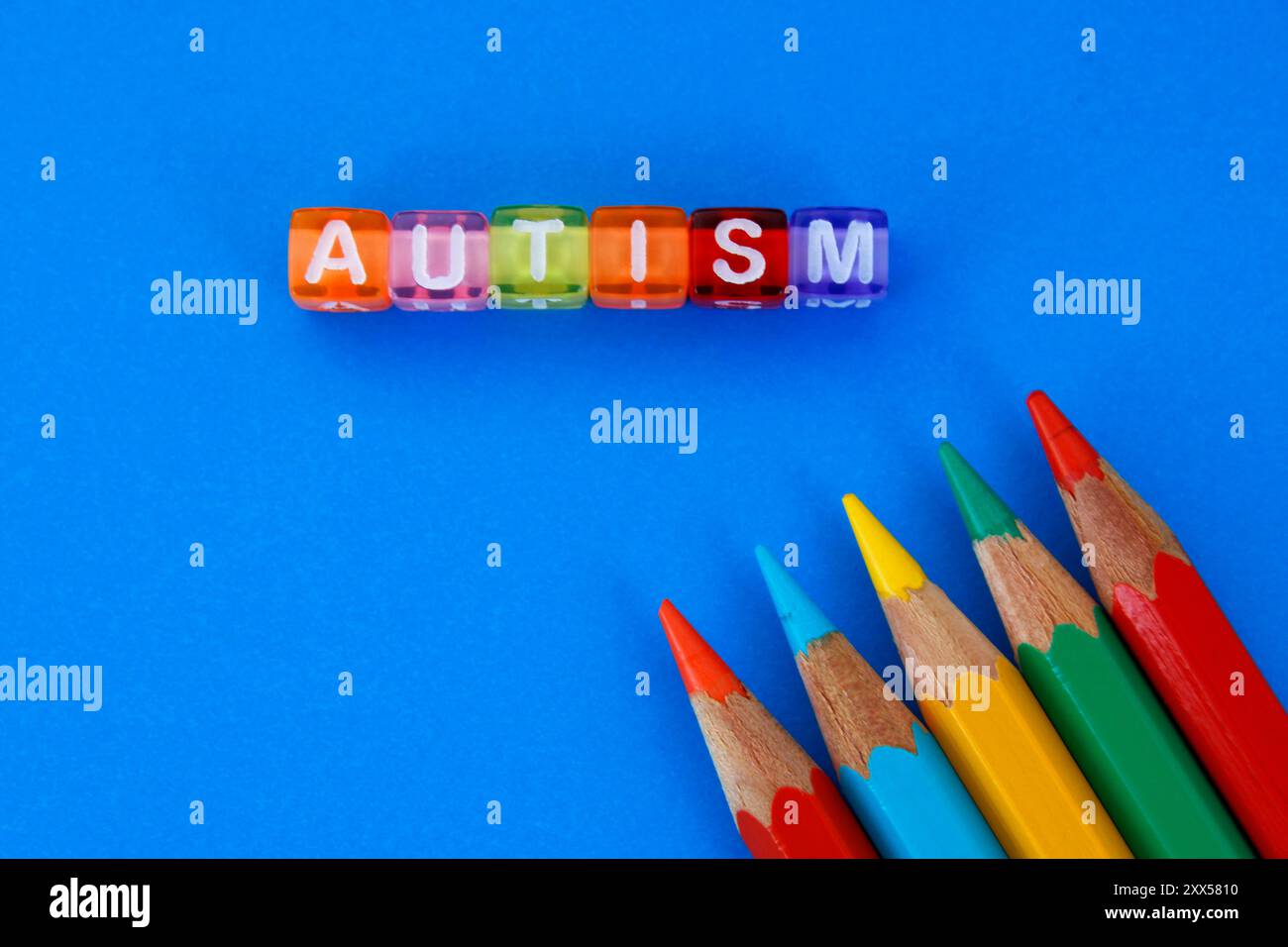 Cubi che formano la parola autismo e matite colorate Foto Stock