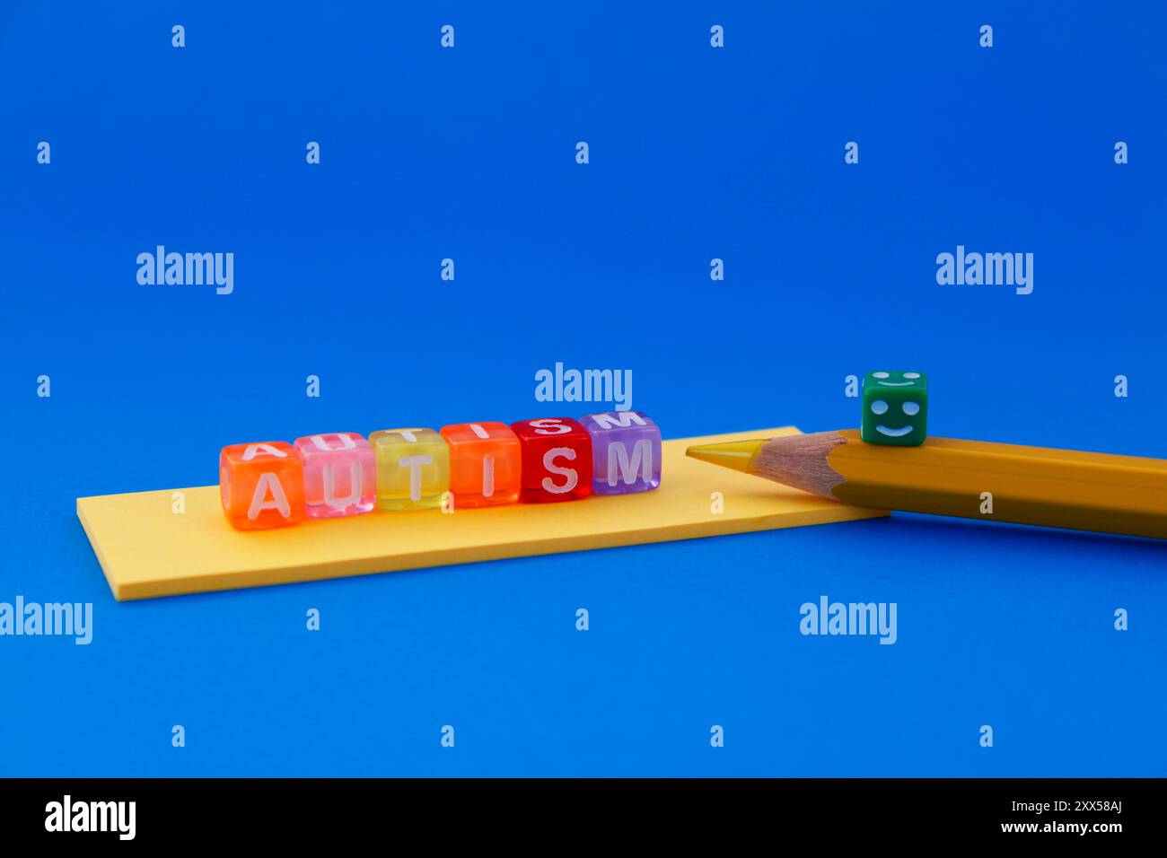 Autismo, faccia felice su matita gialla e cubi colorati Foto Stock